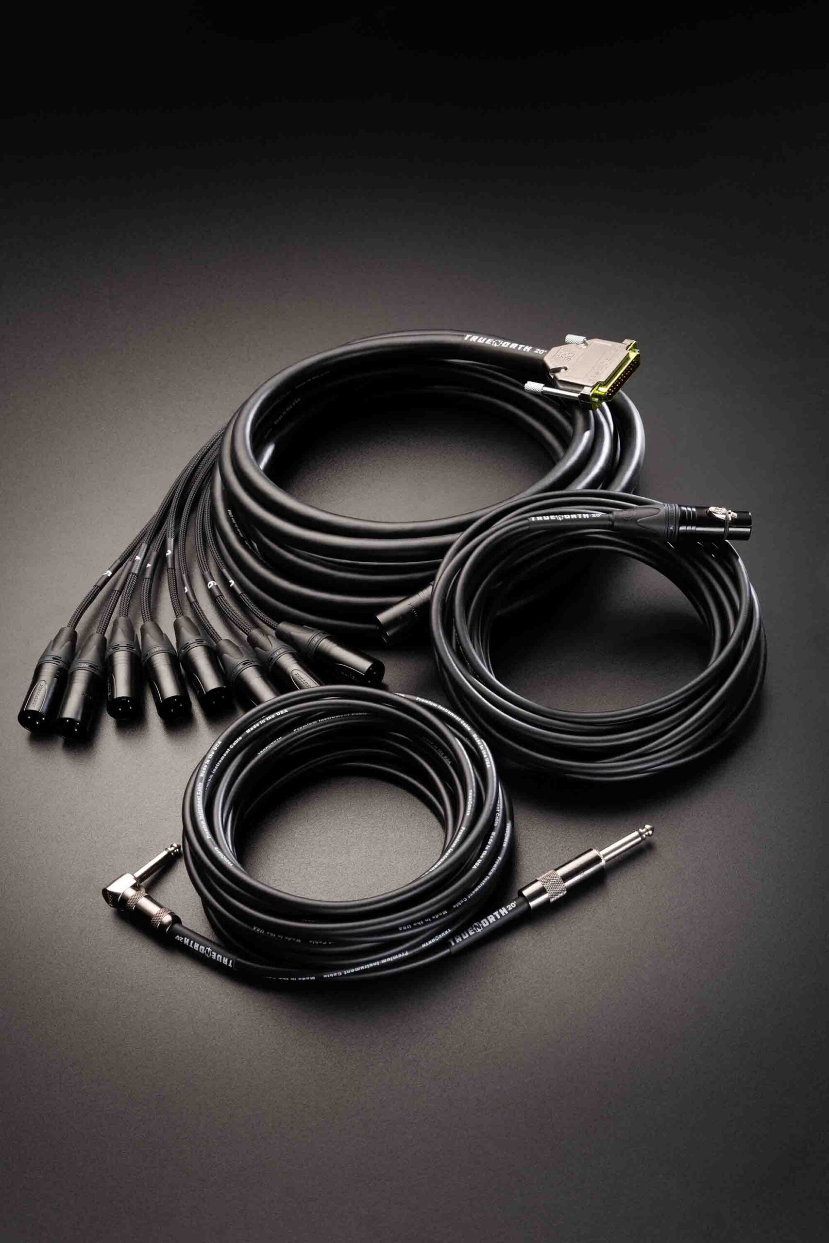 Coiled True North cables with XLR and 1/4-inch instrument connectors on a dark surface